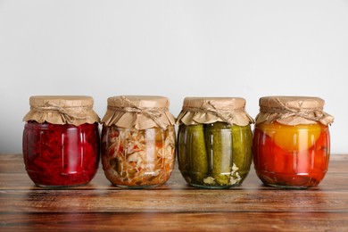 Photo of Jars with different preserved vegetables on wooden table