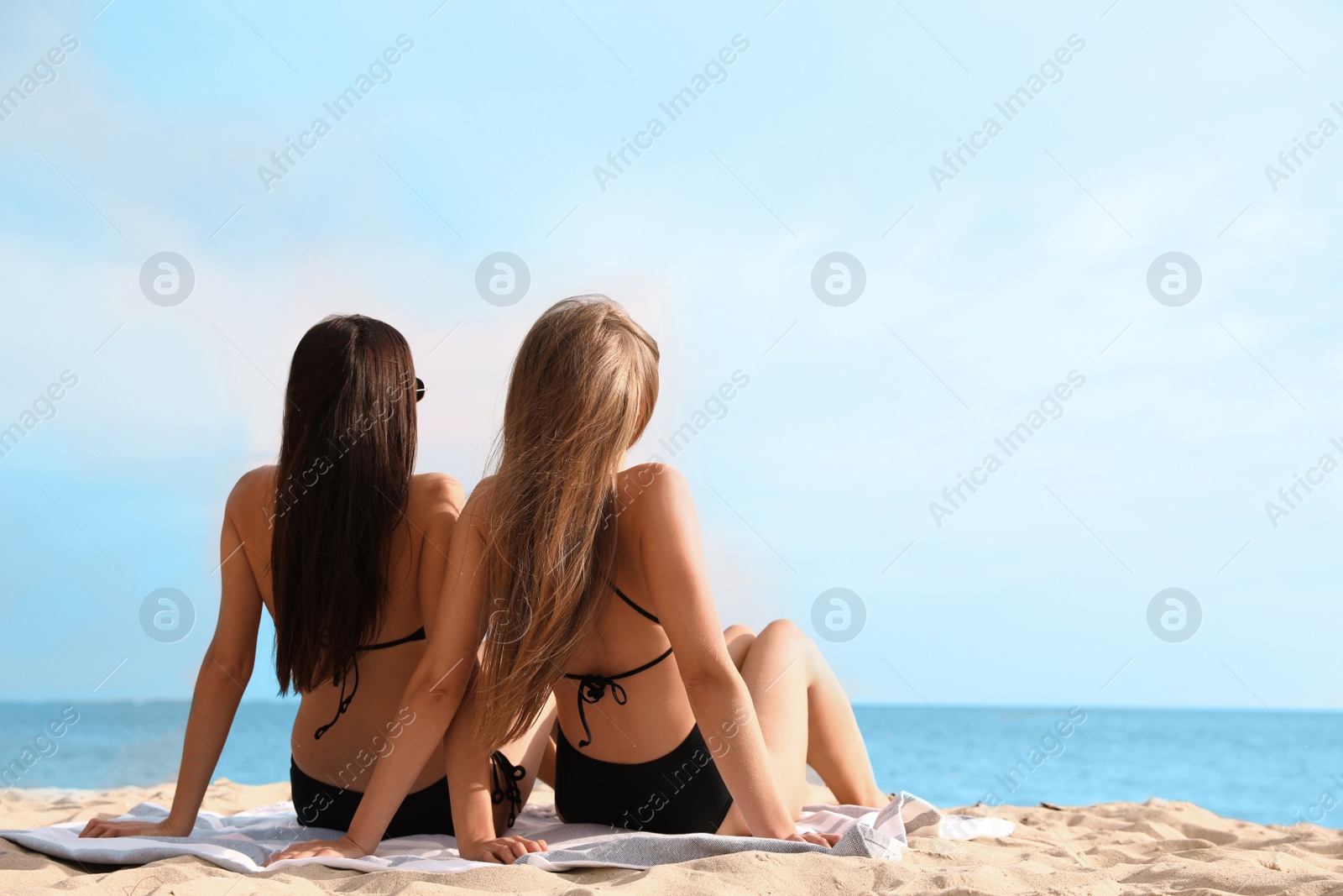 Photo of Young woman in bikini with girlfriend on beach. Lovely couple