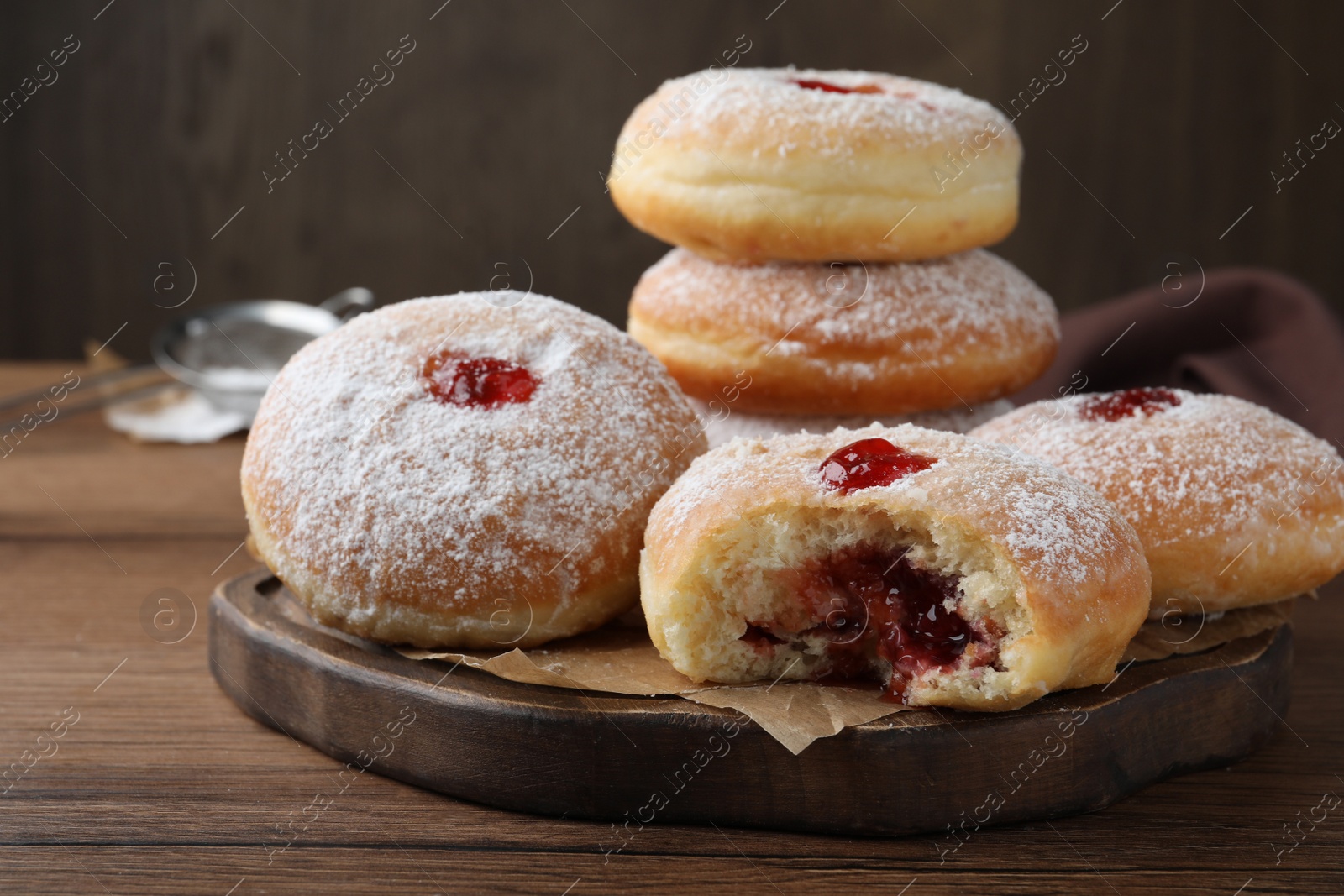 Photo of Delicious donuts with jelly and powdered sugar on wooden table, closeup