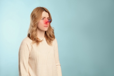 Image of Woman with clothespin on light blue background, space for text. Runny nose concept