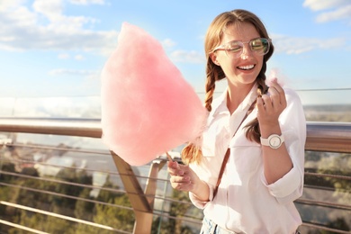 Photo of Young woman with cotton candy outdoors on sunny day