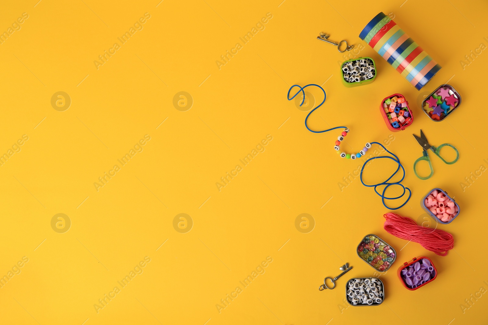 Photo of Kid`s handmade jewelry kit. Colorful beads, bracelet and different supplies on orange background, flat lay. Space for text