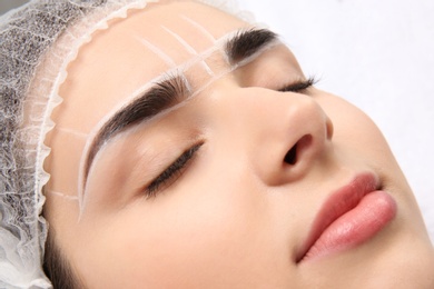 Young woman with marks on face before eyebrow permanent makeup procedure, closeup