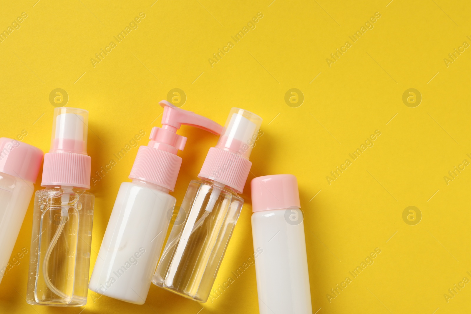 Photo of Cosmetic travel kit on yellow background, flat lay. Space for text