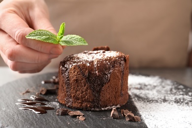 Photo of Chef decorating delicious fresh chocolate fondant with mint at table. Lava cake recipe