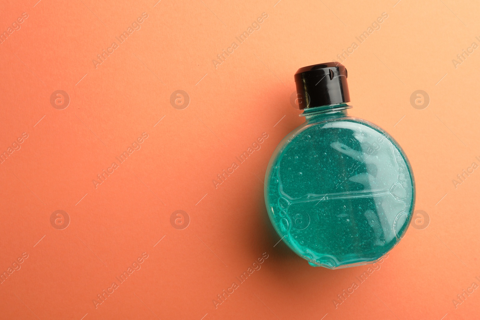 Photo of Bottle of blue cosmetic gel on pale orange background, top view. Space for text