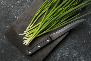 Photo of Fresh green onion and knife on black table, top view