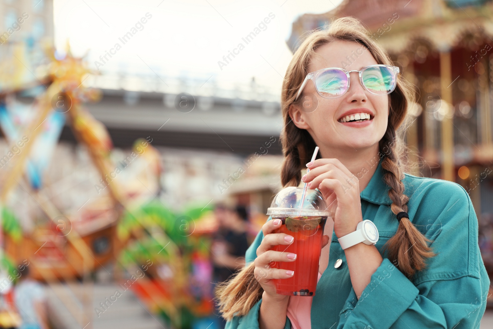 Photo of Young woman with refreshing drink in amusement park. Space for text