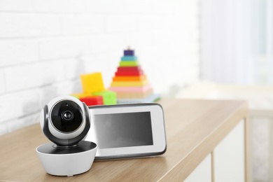 Photo of Baby monitor with camera and toys on chest of drawers in room, space for text. Video nanny