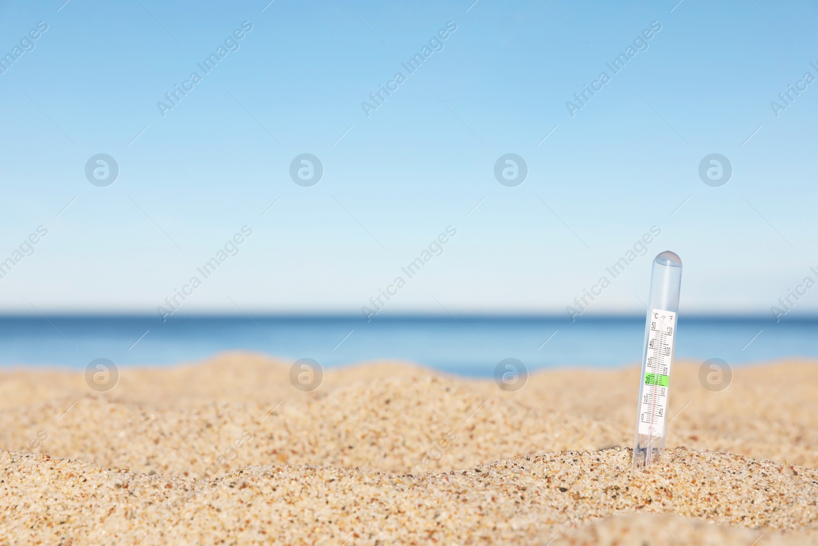 Photo of Weather thermometer in sand near sea, space for text