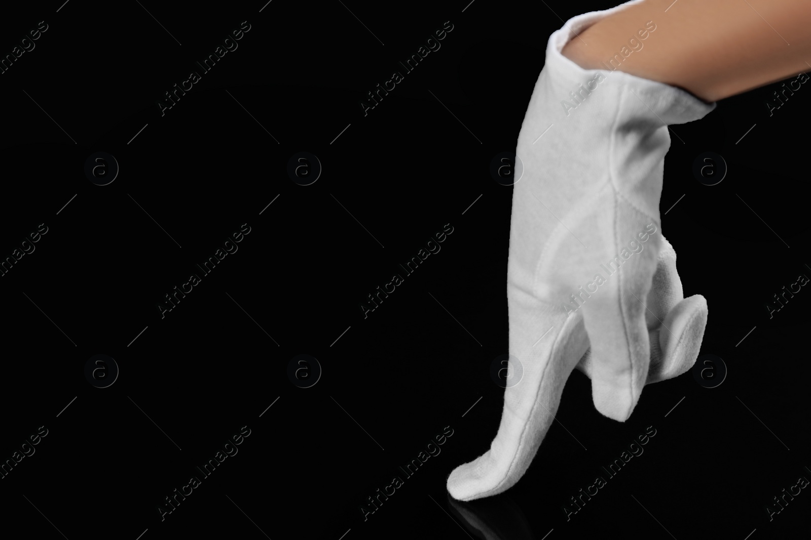 Photo of Person in white glove checking cleanliness on black background, closeup. Space for text
