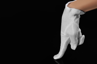 Photo of Person in white glove checking cleanliness on black background, closeup. Space for text