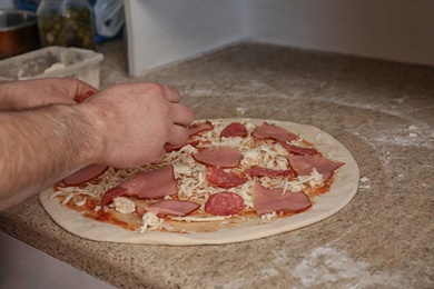 Photo of Man preparing pizza at table, closeup. Oven recipe