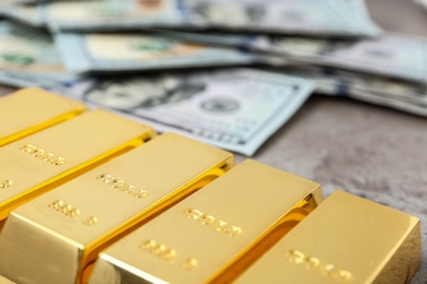 Gold bars and dollar bills on table, closeup