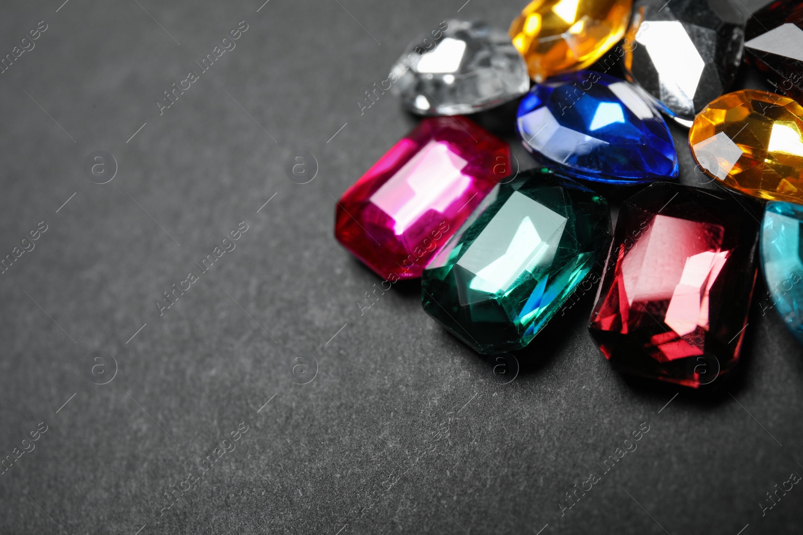 Photo of Pile of different beautiful gemstones on black background, closeup. Space for text