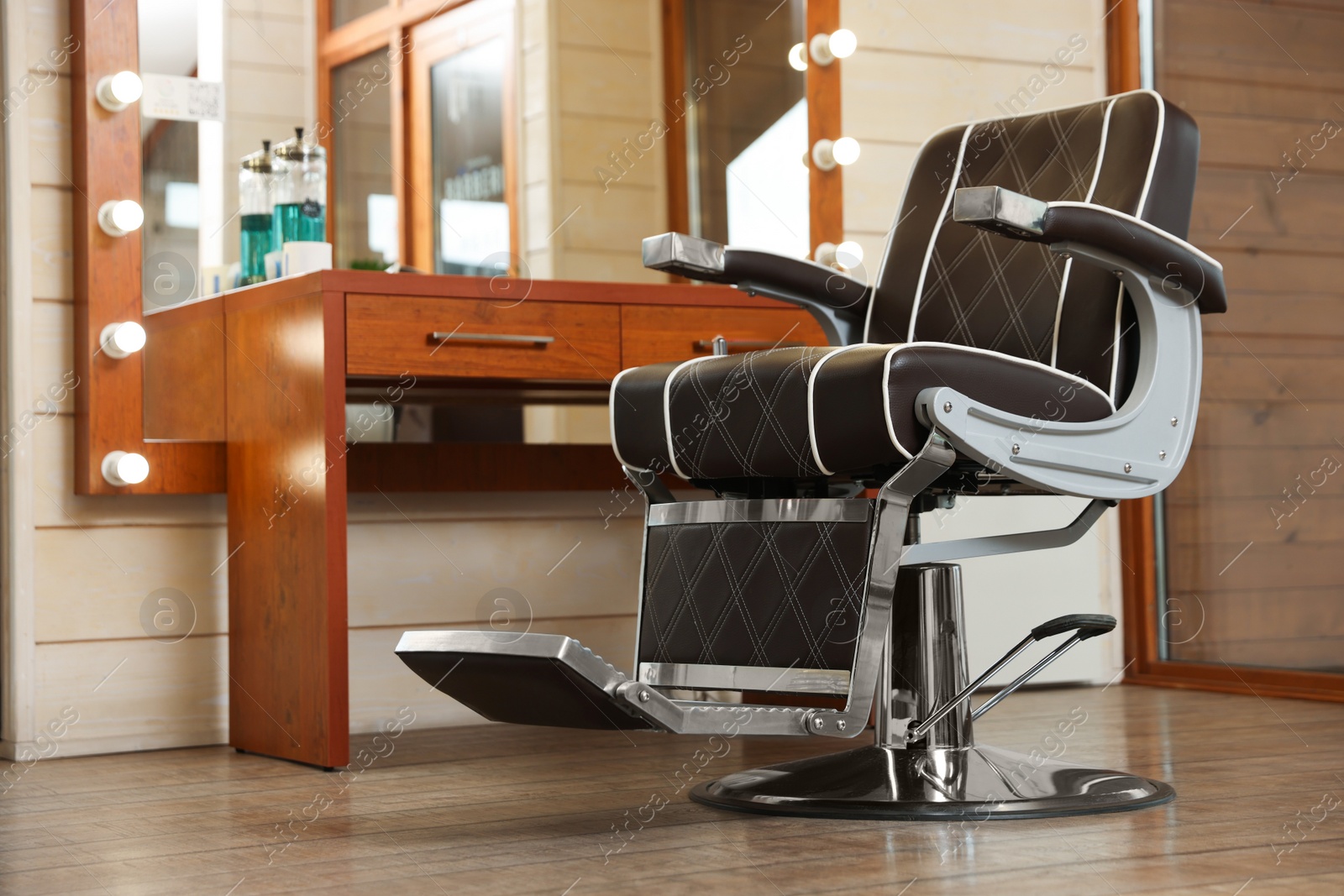 Photo of New empty chair near table with mirror in hairdressing salon