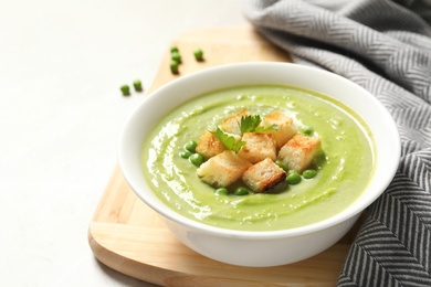 Photo of Fresh vegetable detox soup made of green peas with croutons in dish served on table