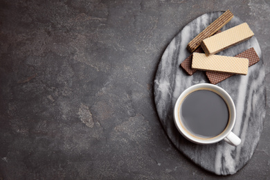 Breakfast with delicious wafers and cup of coffee on grey table, flat lay. Space for text