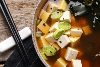 Photo of Bowl of delicious miso soup with tofu served on wooden table, flat lay