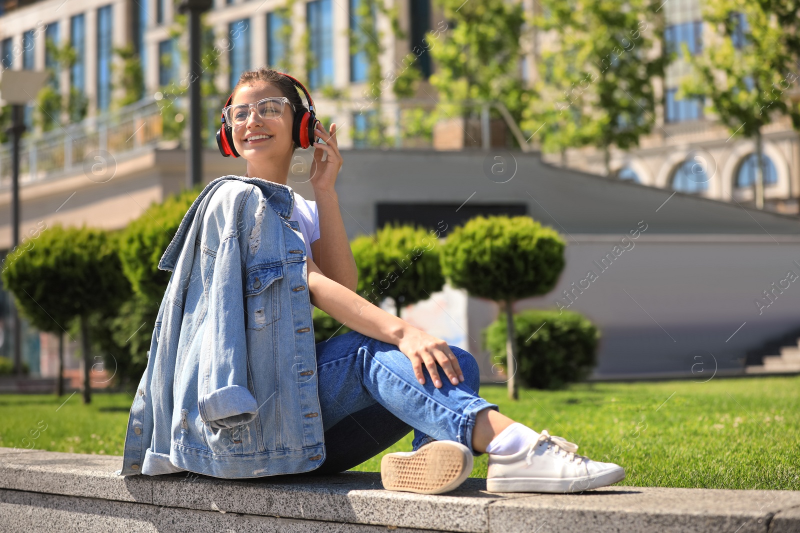 Photo of Young woman with headphones listening to music on city street. Space for text