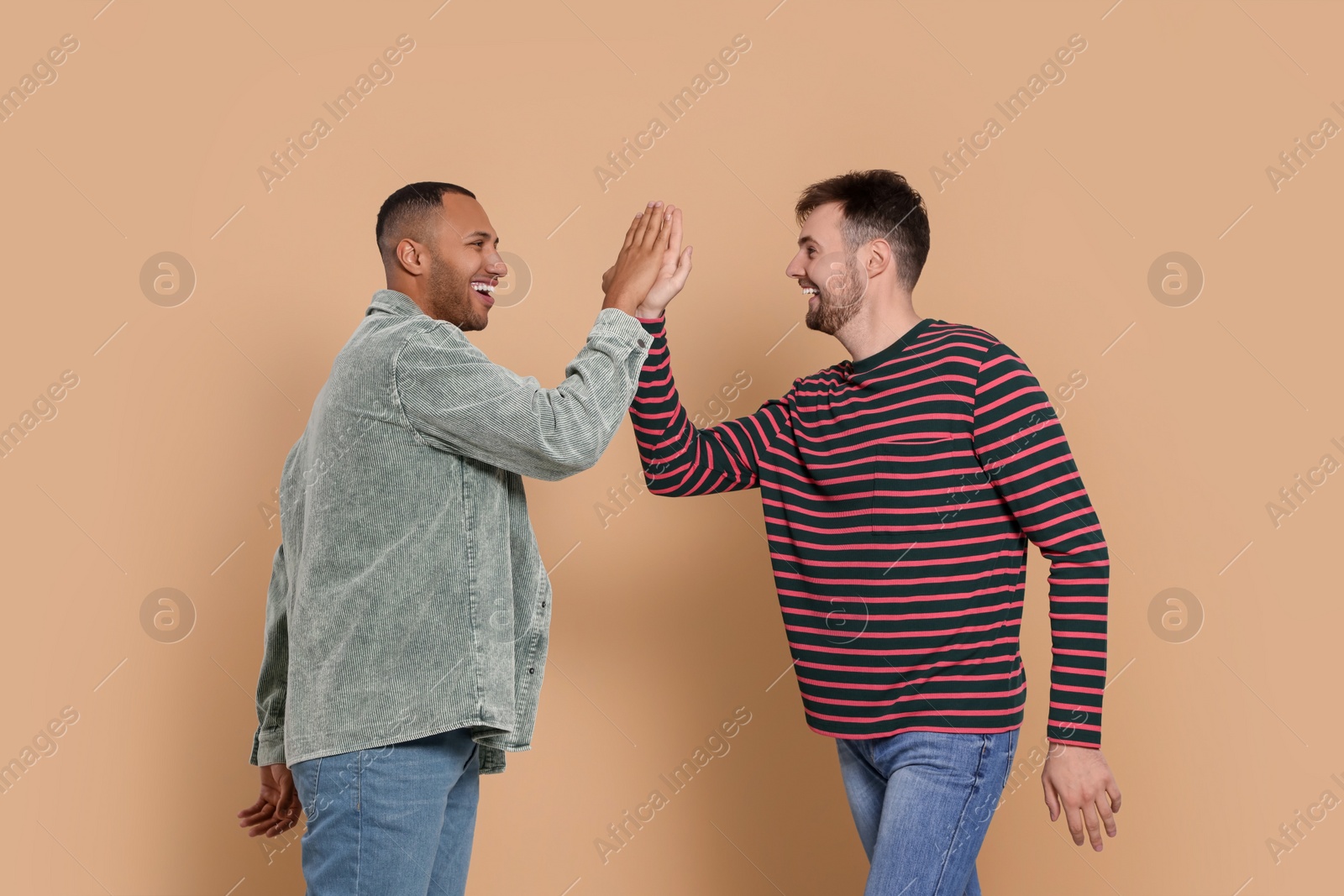 Photo of Men giving high five on beige background