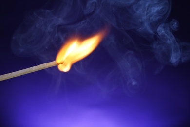Photo of Burning matchstick on color background, closeup. Space for text