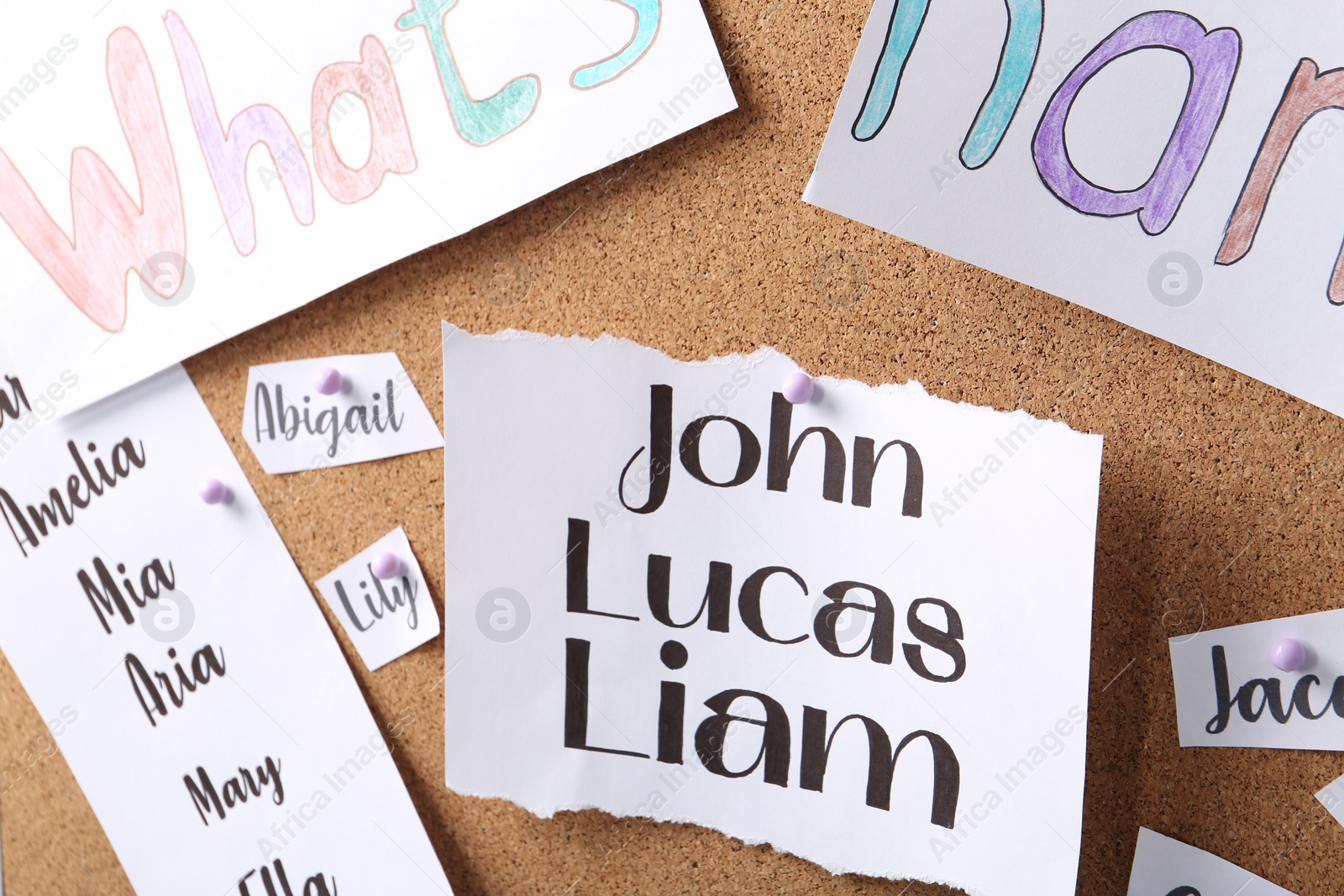 Photo of Paper pieces with baby names on cork board, closeup