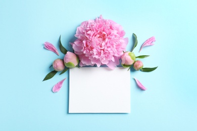 Beautiful peony flowers and blank card on color background