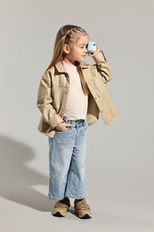 Photo of Fashion concept. Stylish girl with toy camera on light grey background