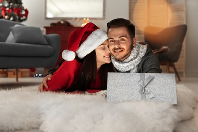 Photo of Young couple with opened Christmas gift box at home