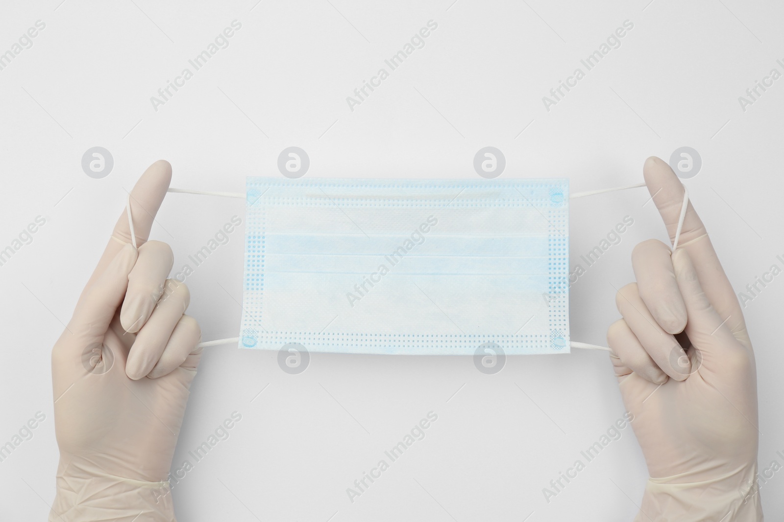 Photo of Doctor in medical gloves holding protective mask on white background, closeup