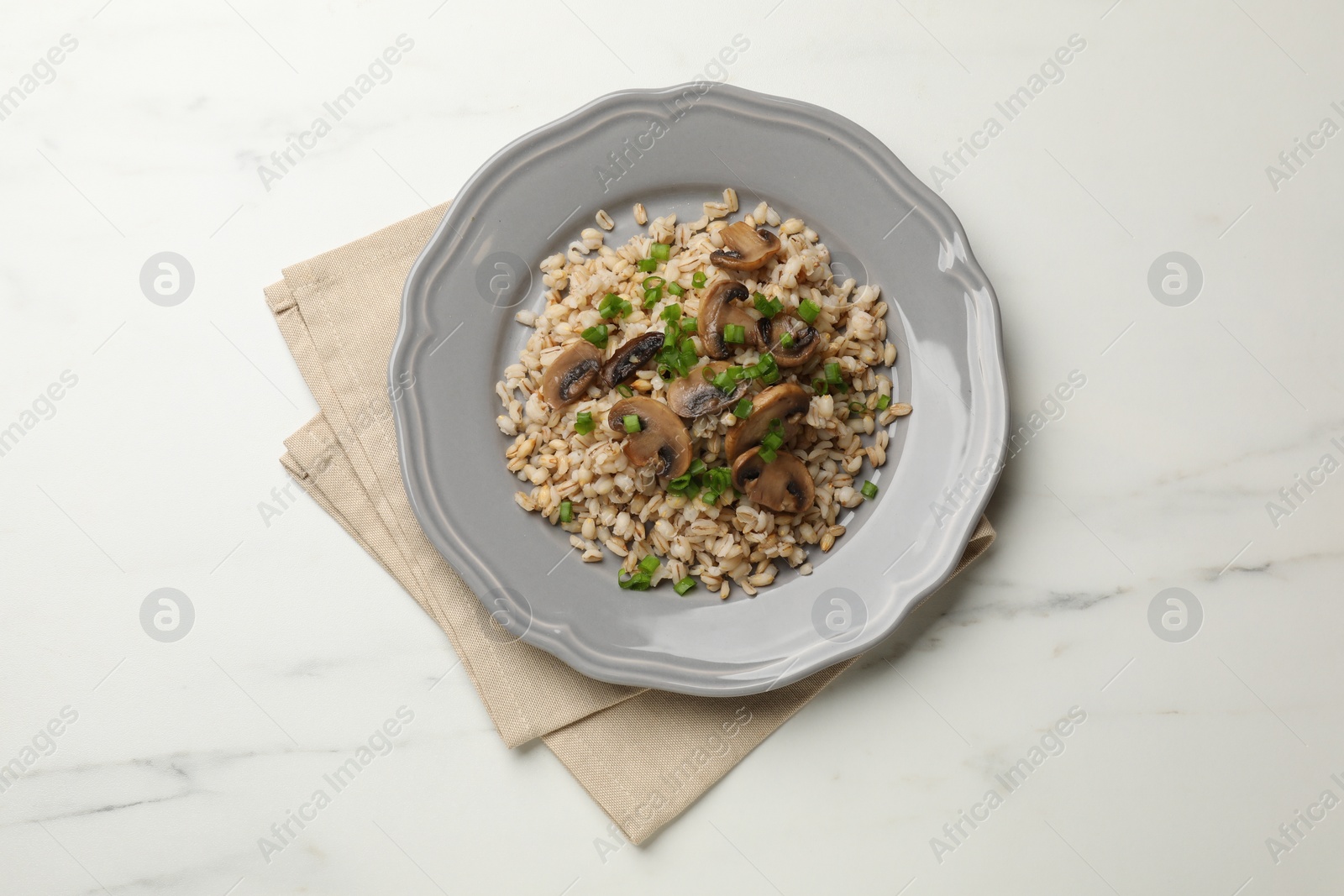 Photo of Delicious pearl barley with onion and mushrooms on white marble table, top view