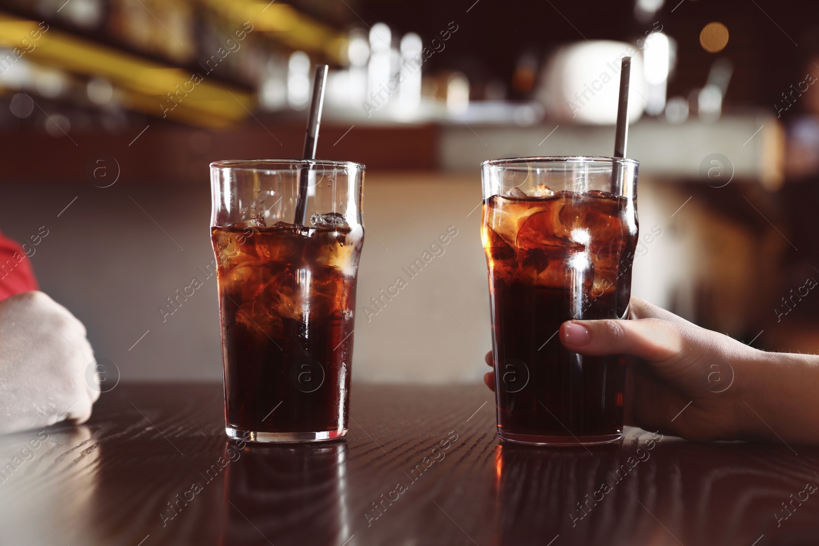 Photo of Young couple with glasses of refreshing cola at table indoors, closeup