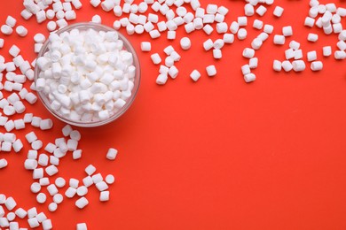 Photo of Bowl with delicious marshmallows on red background, flat lay. Space for text