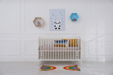 Photo of Cute baby room interior with comfortable crib and picture
