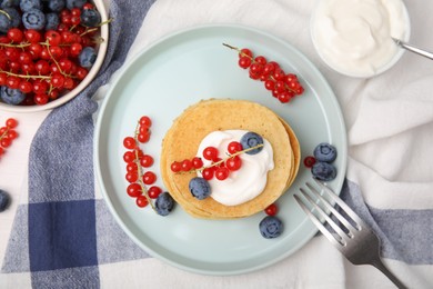 Photo of Tasty pancakes with natural yogurt, blueberries and red currants on table, flat lay