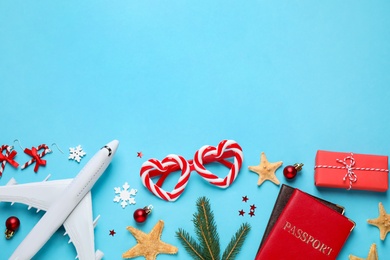 Photo of Flat lay composition with Christmas decorations and passports on light blue background, space for text. Winter vacation