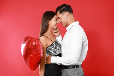 Photo of Beautiful couple with heart shaped balloon on red background
