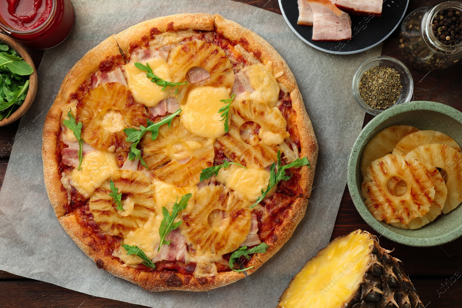 Photo of Delicious pineapple pizza and ingredients on table, flat lay