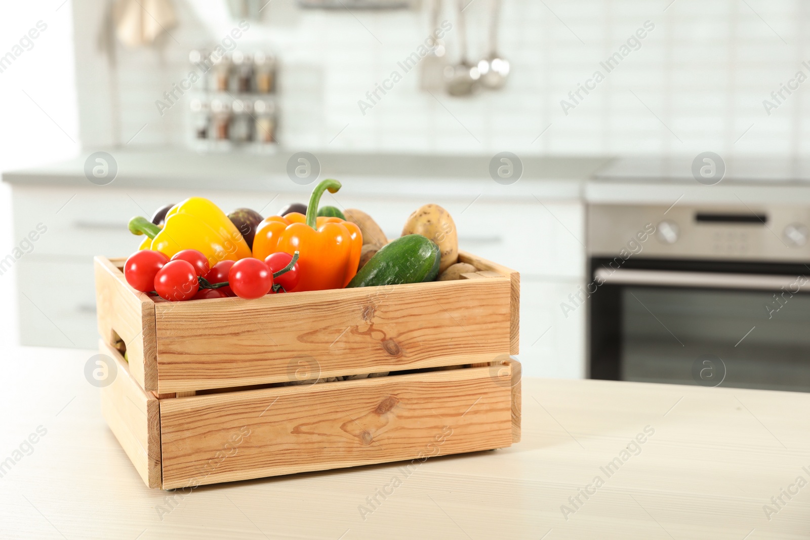 Photo of Wooden crate full of vegetables on table in kitchen. Space for text