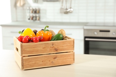 Photo of Wooden crate full of vegetables on table in kitchen. Space for text