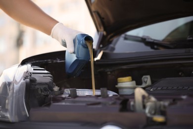 Photo of Man pouring motor oil from blue container, closeup. Space for text