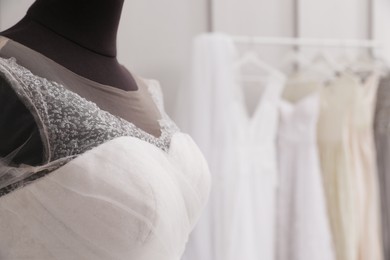 Photo of Mannequin with beautiful wedding dress in atelier, closeup. Space for text