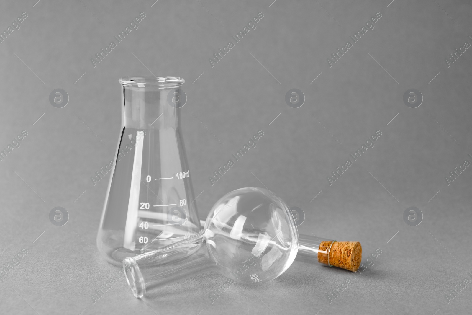 Photo of Different laboratory glassware on grey background, space for text