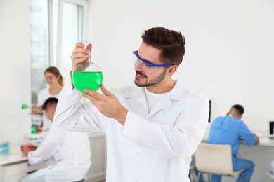 Medical student with glass flask working in modern scientific laboratory