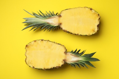 Photo of Halves of fresh pineapple on yellow background, top view