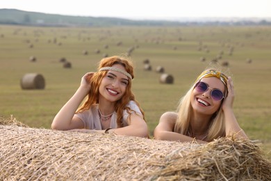 Beautiful hippie women near hay bale in field