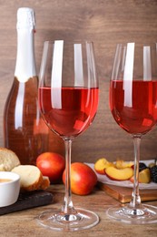 Photo of Delicious rose wine and snacks on wooden table