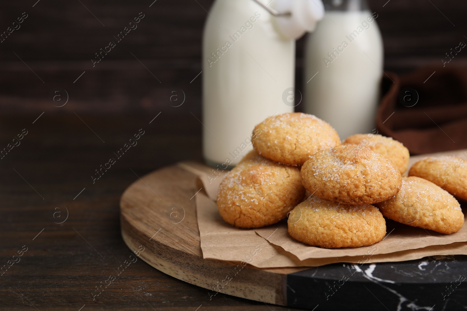 Photo of Tasty sweet sugar cookies and milk on wooden table, closeup. Space for text