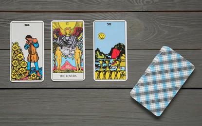 Photo of Tarot cards on grey wooden table, flat lay